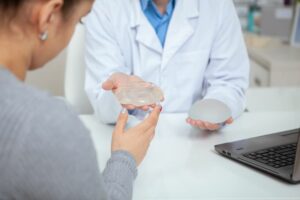 Cropped shot of a female patient examining silicone breast implants, during medical appointment with her plastic surgeon