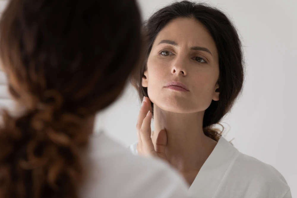 woman looking at her face in the mirror