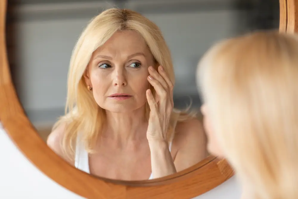 middle aged woman checking her face in the mirror